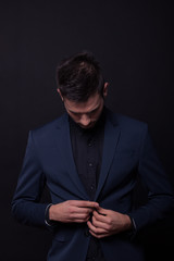 young man model looking down buttoning jacket suit