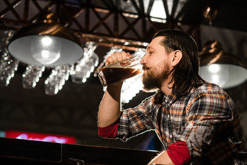 hipster bearded man in a plaid shirt drinking beer