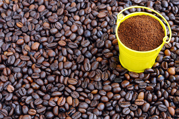 Roasted coffee beans and a small bucket with ground coffee.