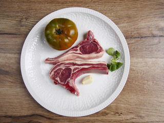 Two lamb chops wiht tomato and garlic in a plate
