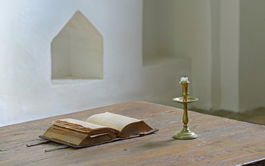 Very old open bible on table in medieval church