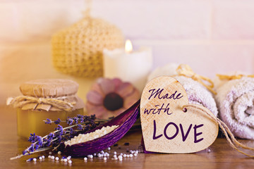 Spa and wellness setting with white towels , sponge, candle, lavender and wooden heart on bricks wall background. Valentine's postcard