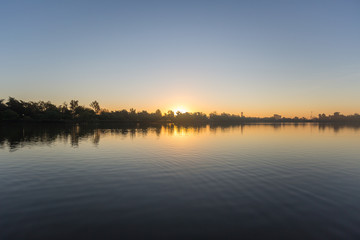 Sol ocultándose entre los árboles a la orilla de un lago