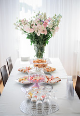White bouquet made of lilies and roses stands in tall vase on ta