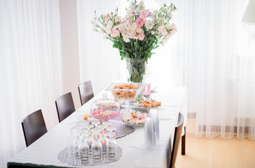White bouquet made of lilies and roses stands in tall vase on ta