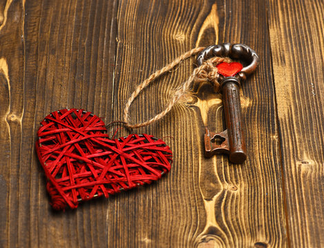 red heart and metallic key on wood as valentines decoration