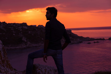 Fototapeta premium man standing thinking back light sunset lighting side view profile silhouette summer evening beach