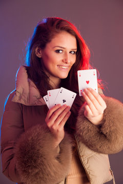 Beautiful brunette holding four aces as a sign for poker game, g