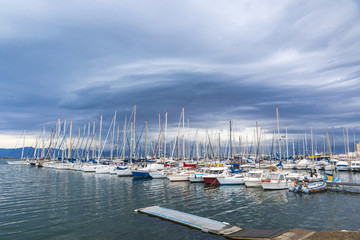 Small fishing and recriational boats docked in the Port of Cagliari, Sardinia, Italy. Overcast cloudy sky on the background