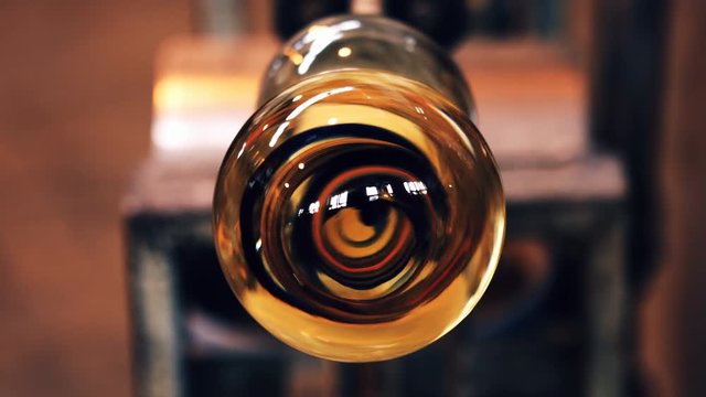 Close-up of molten glass on a blowpipe at glassblowing factory