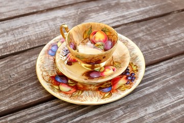 Vintage tea cup with fruit decor on old wood