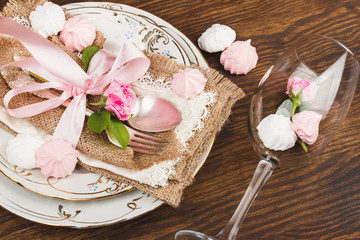 Light pink roses and tableware on the wooden table