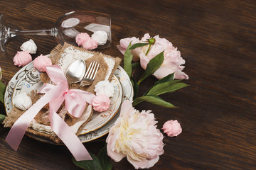 Light pink peonies and tableware on the wooden table