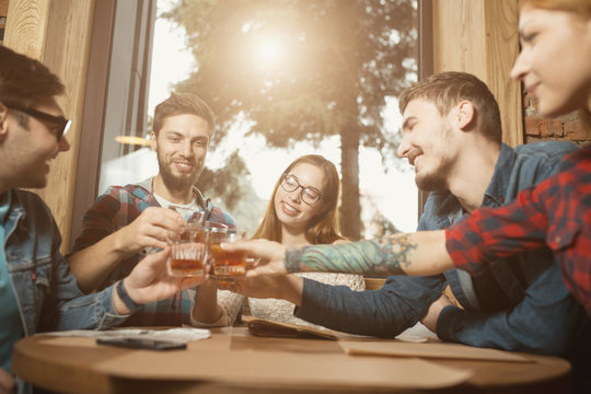 Groups of friends celebrating birthday sitting in cafe, clink glasses
