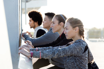 Portrait of running people doing stretching in the city.