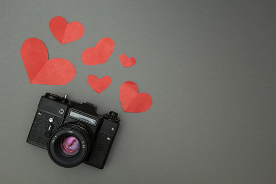 Black retro camera on a black background and red heart.