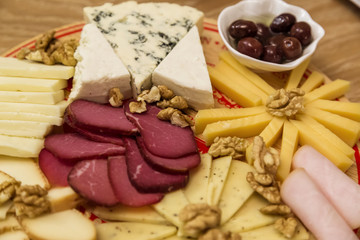 Fototapeta na wymiar Cheese Board over Wooden Table With smoked meat