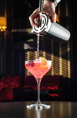 Foto op Plexiglas Barman at work, preparing cocktails. pouring cosmopolitan to cocktail glass. © suvorovalex
