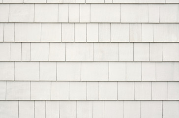 Neutral white or tan siding on a house or building. Straight parallel lines. Outdoor siding with highlights.. Roofing or construction material.
