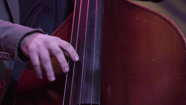 Hand of the musician on the bass strings in slow motion, A man playing the double bass.