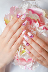Closeup photo of a beautiful female hands with pink nail art design manicure and flower. - 134066382