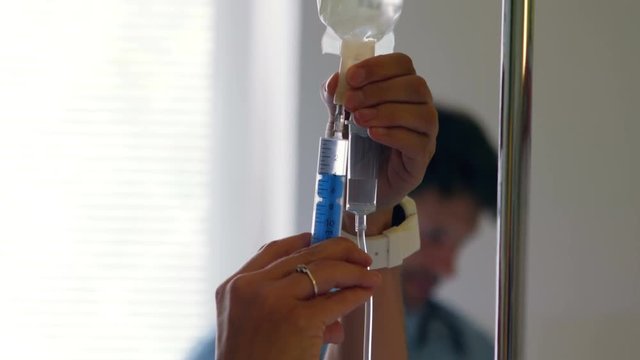 Nurse injecting medicine in infusion