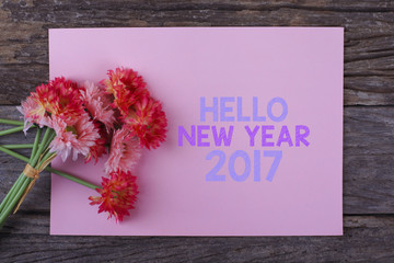 HELLO NEW YEAR 2017  WRITTEN ON A PIECE OF PAPER WITH PINK FLOWER