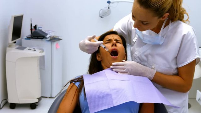 Dentist injecting female patient in mouth