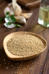 Raw organic white quinoa (lat. Chenopodium quinoa) seeds on wooden plate, photographed with natural light (Selective Focus, Focus one third into the quinoa seeds)