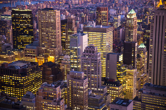 Night view of skyscrapers and buildings across New York City with lights.