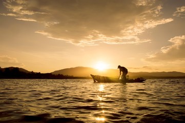 Silhouette of fisherman throwing fishing net in Thailand