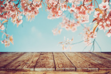 Naklejka na ściany i meble Top of wood table with pink cherry blossom flower (sakura) on sky background in spring season - Empty ready for your product and food display or montage. vintage color tone.