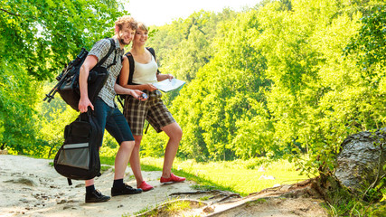 Naklejka na ściany i meble Hiking backpacking couple reading map on trip.