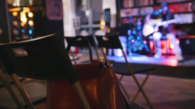 Bag is on the chair - empty room in front of the guitarist at concert - acoustic guitar, microphone, club