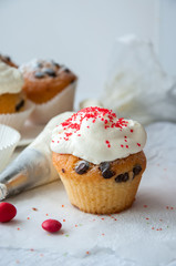 Vanilla cupcakes with chocolate chips and whipped cream frosting sprinkled with red colored sugar on the white background