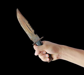 Hand holding rusty old knife with black leather handle isolated on a black background