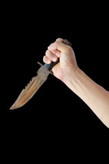 Hand holding rusty old knife with black leather handle isolated on a black background