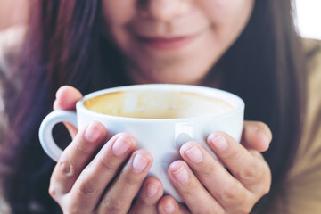 Closeup image of asian woman drinking hot coffee with feeling good