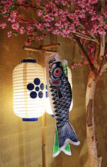 Japanese lantern with koi fish flag hanging under sakura tree