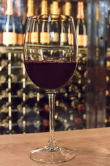 Red wine glass in front of blurred rack