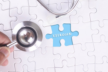 A doctor holding a Stethoscope on missing puzzle WITH ESTROGEN W
