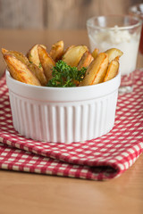 Potato wedge in bowl with sauce.