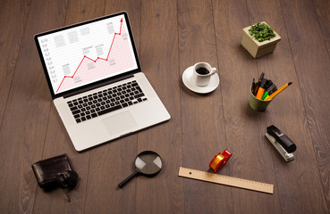 Computer desk with laptop and red arrow chart in screen