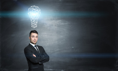 Businessman on black chalkboard background with a glowing gridshell bulb above him.