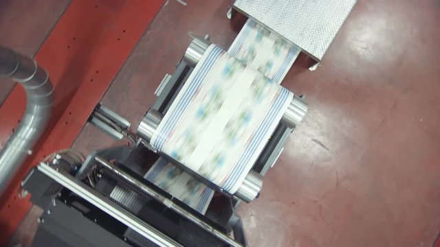 Crane shot of offset printing press working at high speed printing paper products