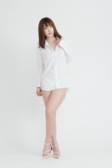 白いシャツを着た女性。女性は足の素肌を見せています。スタジオ撮影。白背景。