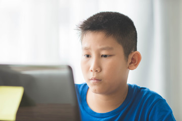Young Asian boy using laptop technology at home.