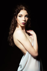 Naklejka premium Dramatic portrait of sensual young woman among darkness