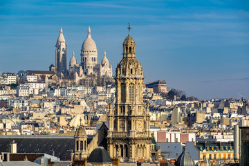 Fototapeta na wymiar Rooftops of Paris with view of the Sacre Coeur Basilica in Montmartre and the Trinity Church. 18th Arrondissement, Paris, France