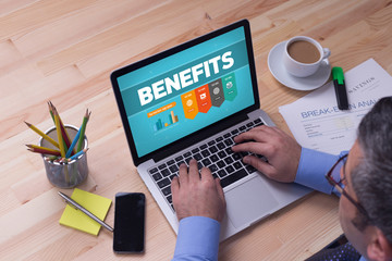 Man working on laptop with BENEFITS on a screen